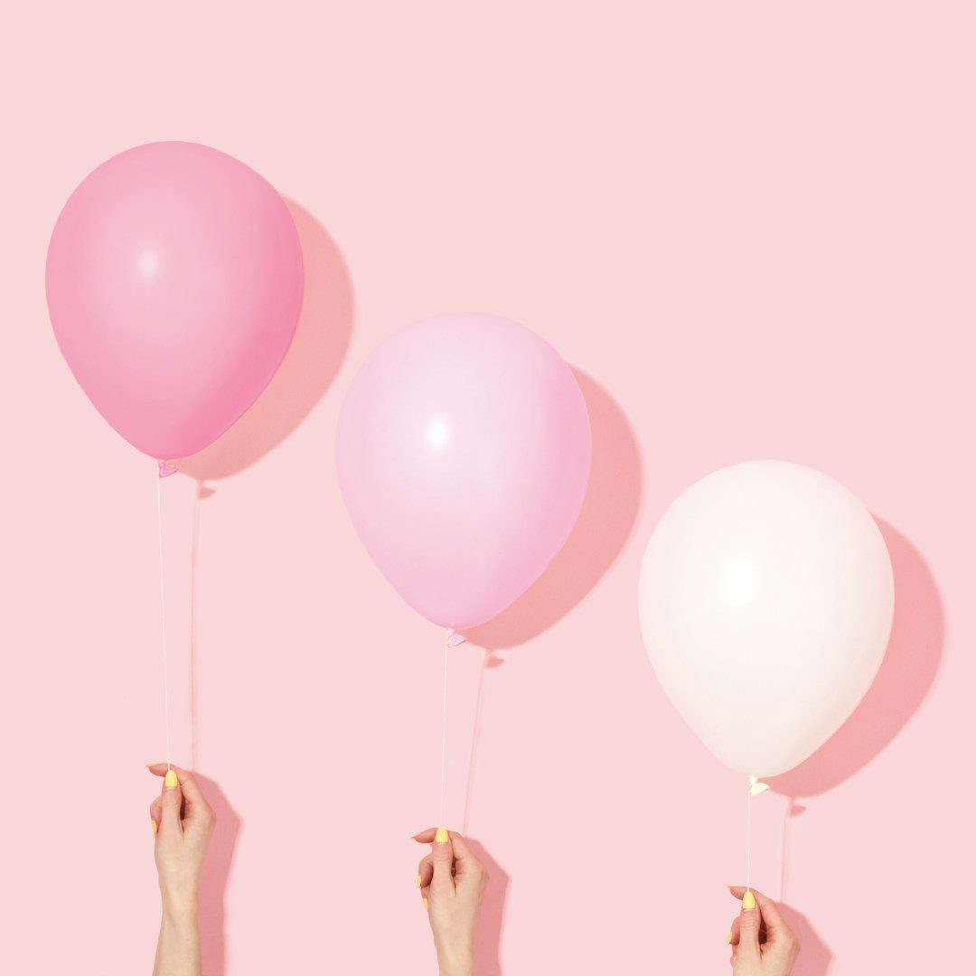 Ablauf Coaching BAFA Prozess Drei Ballons in Rosa und Weiß, gehalten von Händen vor einem pinken Hintergrund.