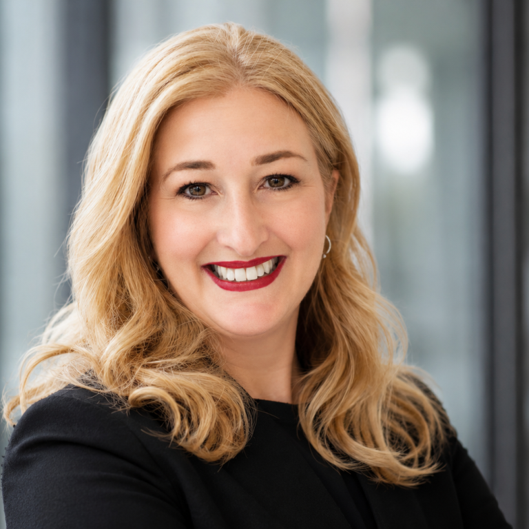 Lächelnde Frau mit langen blonden Haaren in schwarzem Blazer.